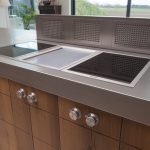 Massief rustieke eiken keuken, op maat gemaakt. De achterwand van de keuken heeft een kast met open vakken. Het RVS kookeiland is voorzien van eiken laden.